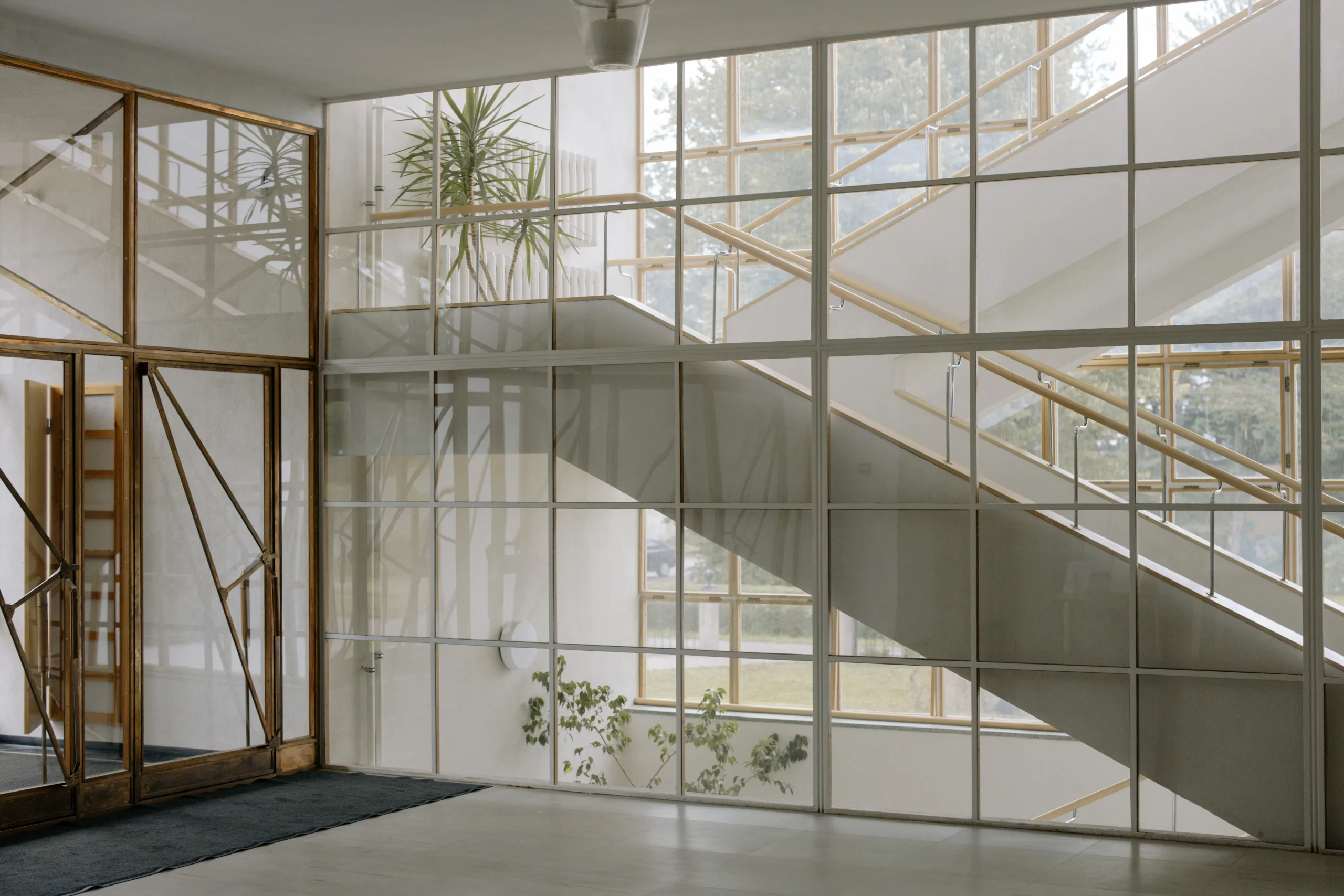 Vestíbulo contemporáneo con escalera inclinada y muro de vidrio
