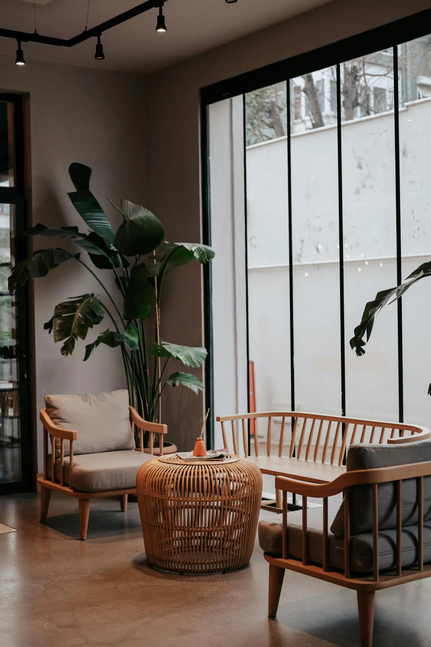 Sala de Estar con Mobiliario Natural y Ventanales de Hierro Forjado