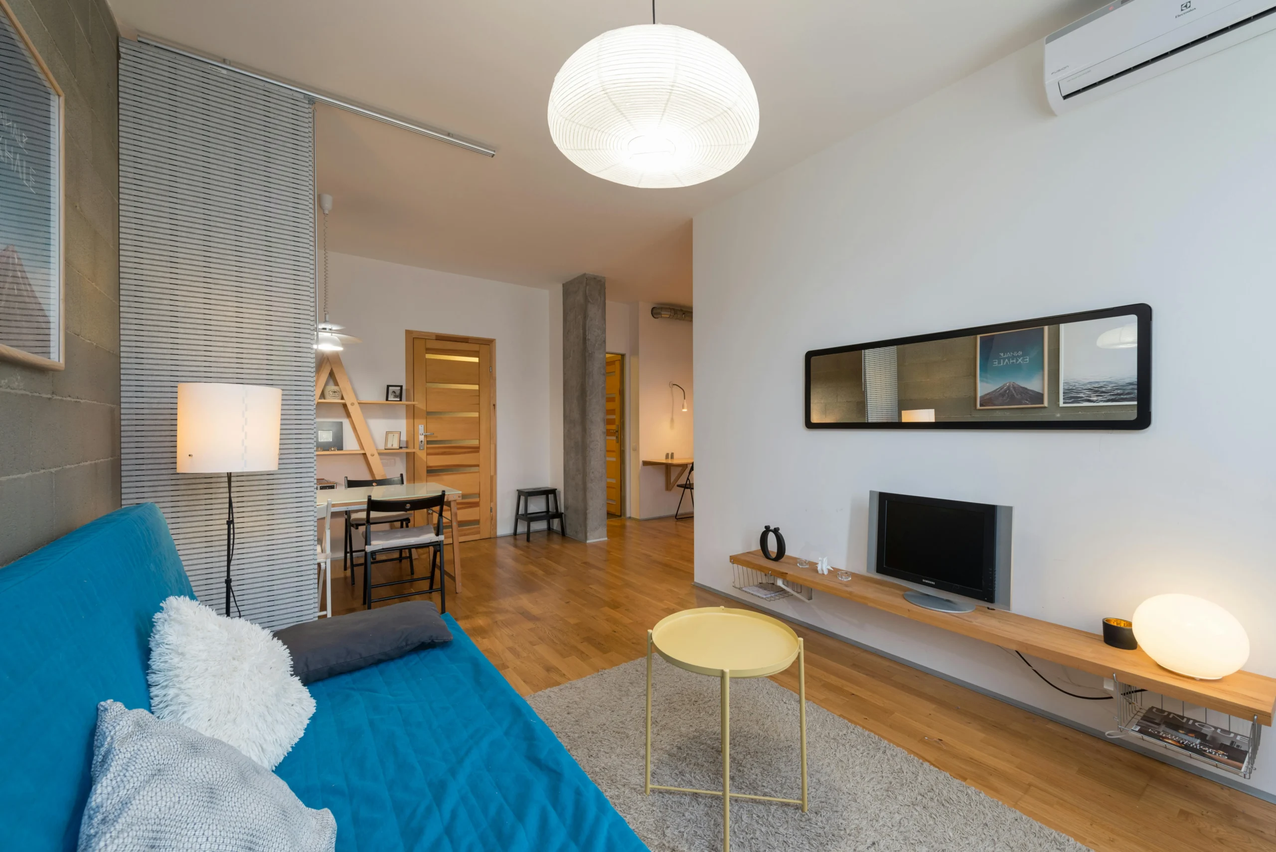 7 Estrategias para iluminar tu casa como una revista. Sala Ecléctica con Sofá Azul y Toques de Madera Natural