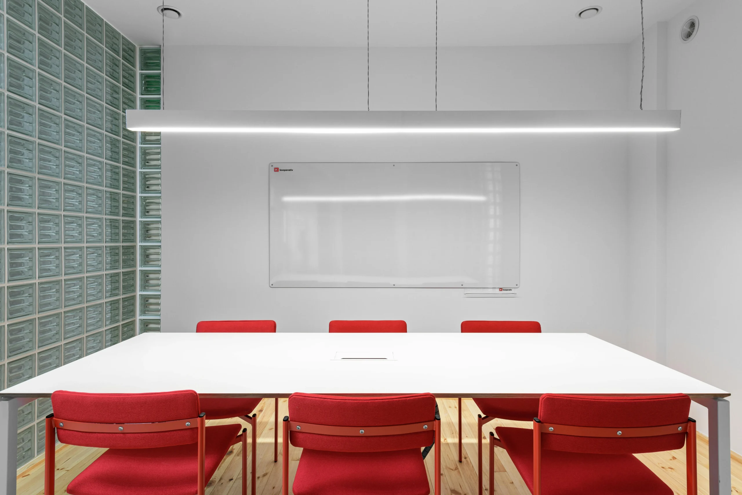 Sala de Reuniones con Pared de Bloques de Vidrio y Sillas Rojas