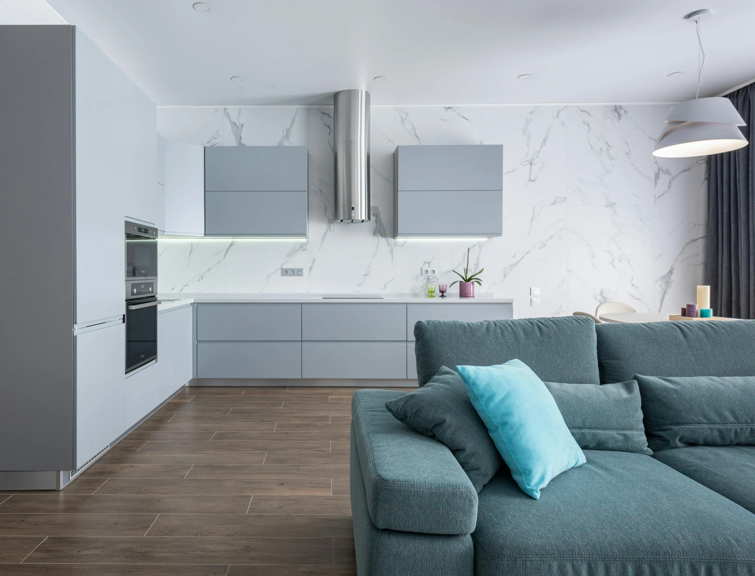 Cocina Abierta en Gris Claro y Mármol con Sofá Azul Turquesa