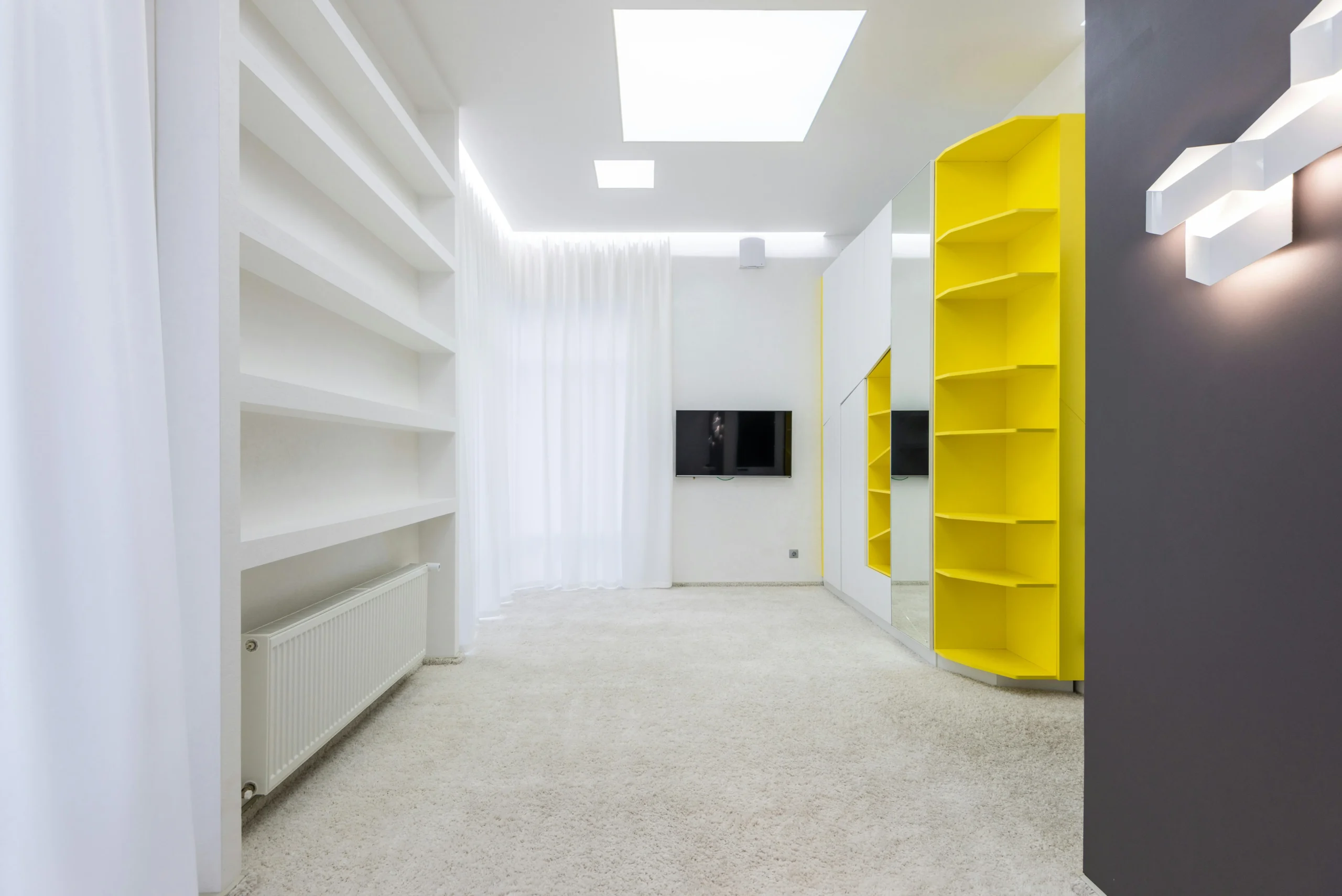 Sala Minimalista con Estanterías Integradas y Toques Amarillos