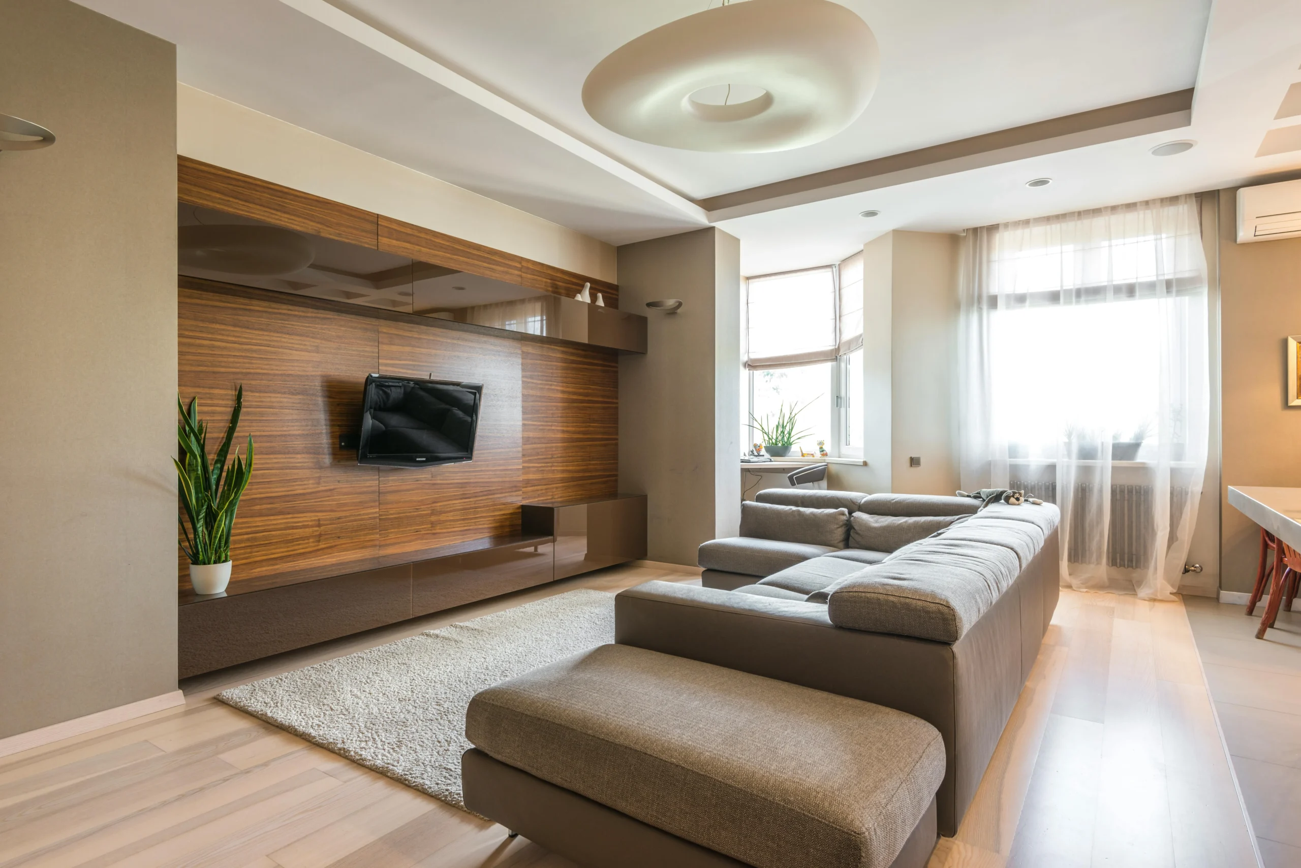 Sala de Estar Moderna con Sofá en L y Panel de Madera 