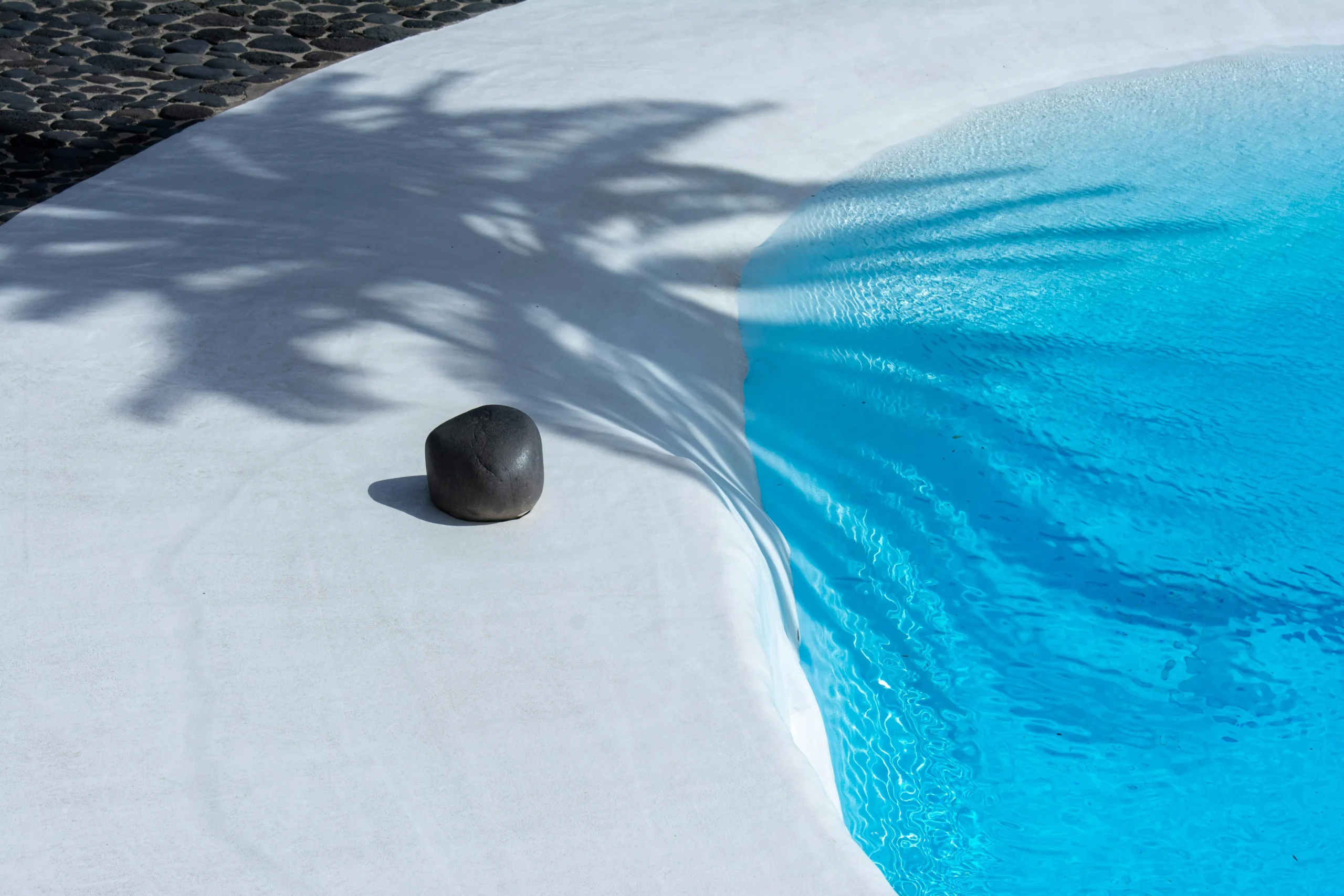 Piscina minimalista con borde orgánico y piedra volcánica