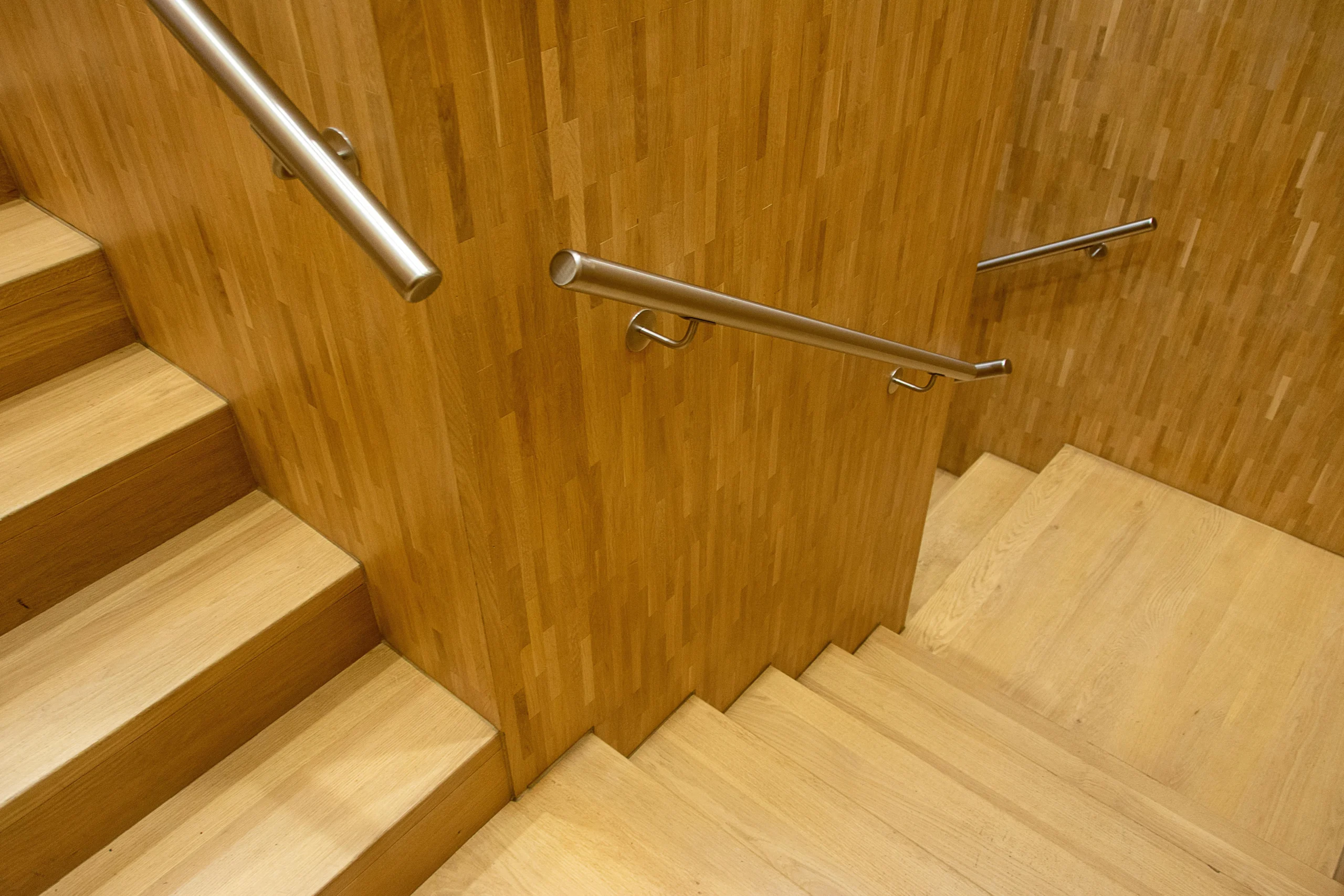 Escalera contemporánea en madera clara con barandillas metálicas