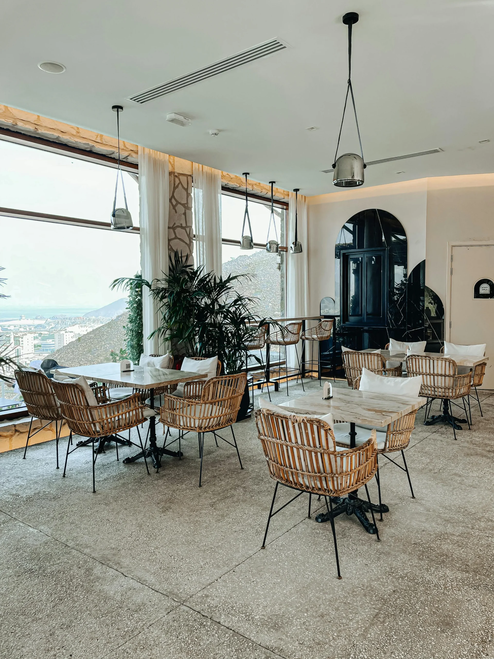 Restaurante Panorámico con Mobiliario de Ratán y Luz Natural