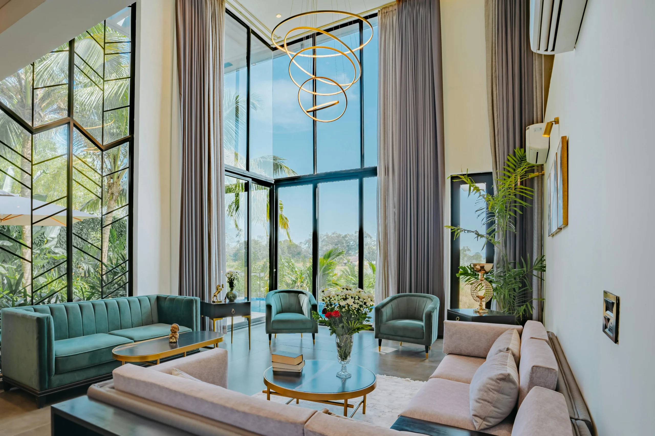 Salón de Doble Altura con Sofás Verdes y Lámpara Escultural Dorada