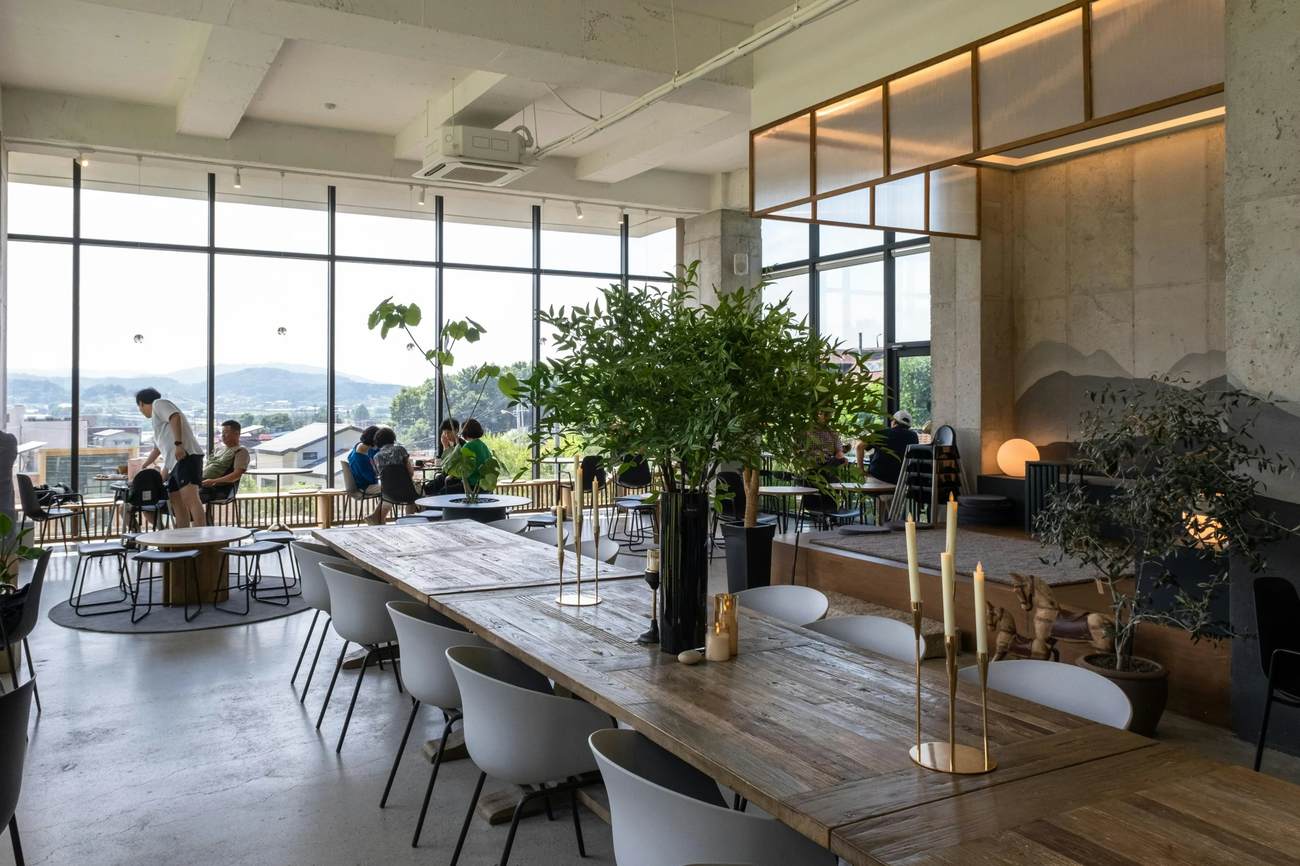 Cafetería Contemporánea con Mobiliario Natural y Luz Panorámica