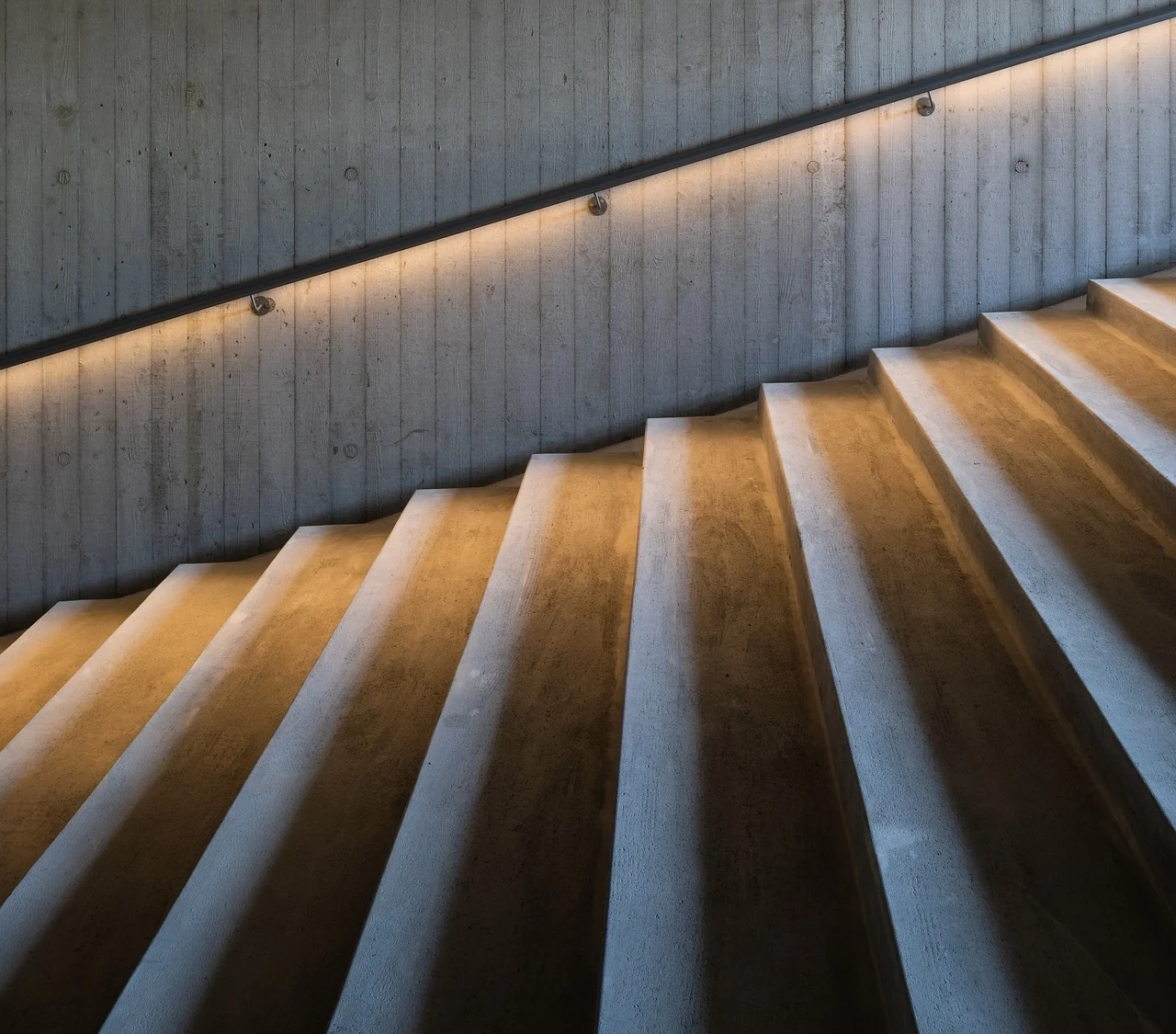 Escalera de concreto con iluminación indirecta en pasamanos