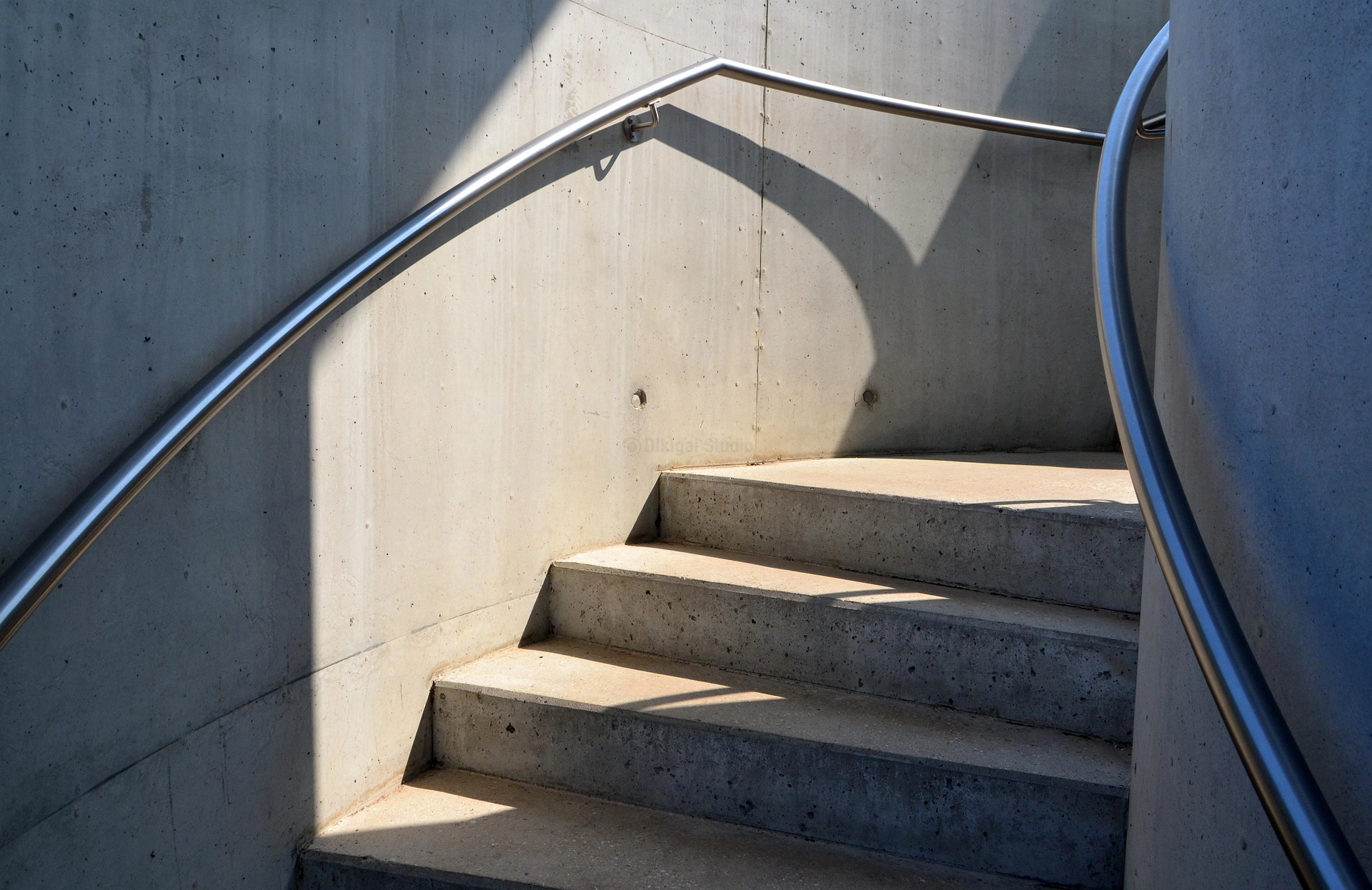 Escaleras curva en hormigón visto con barandal metálico