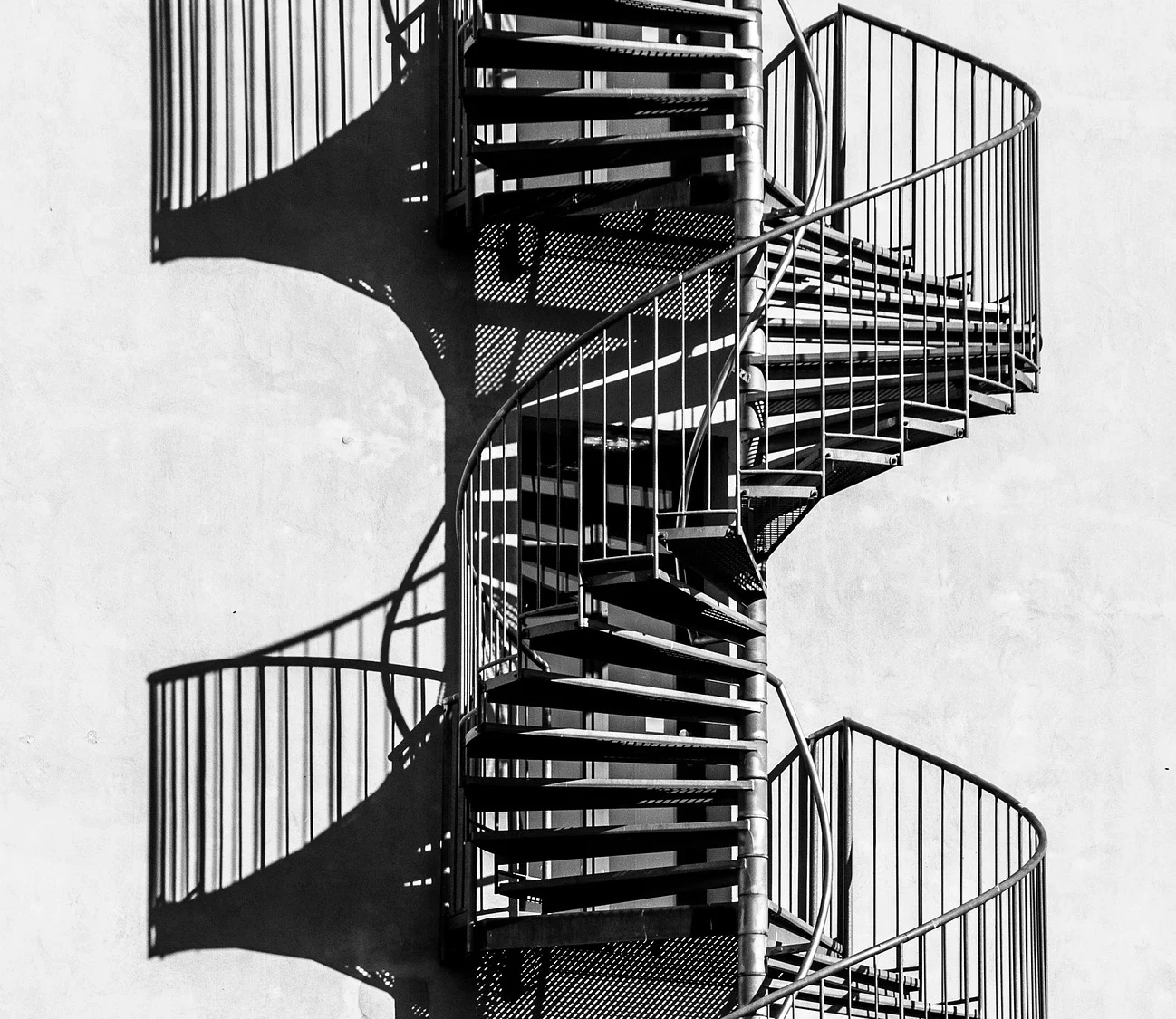 Escalera helicoidal exterior en hierro forjado con sombras gráficas