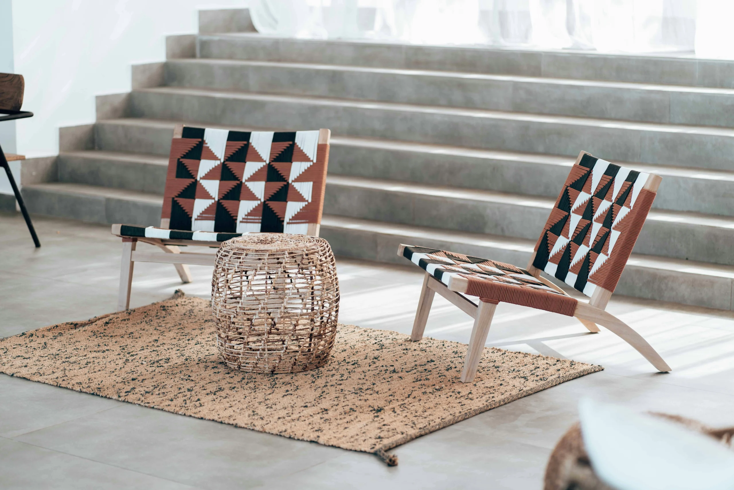 Interiorismo contemporáneo con sillones tejidos y escalera de hormigón