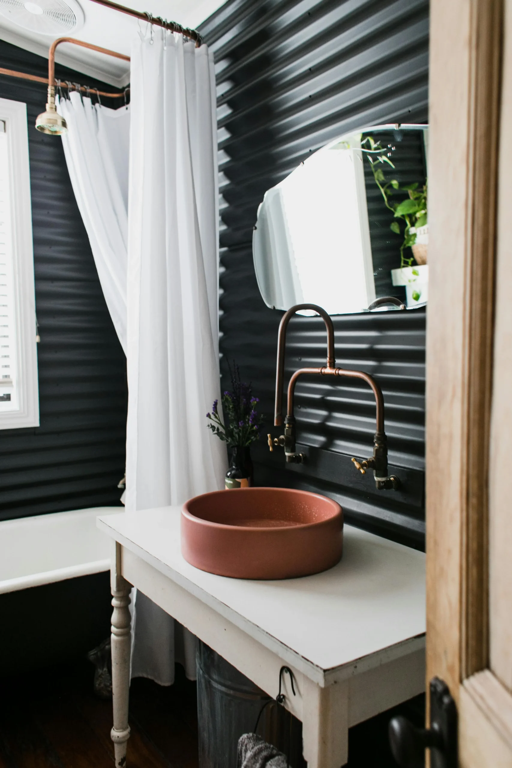 Tendencias para Diseñar Baños en 2026 Baño Rústico-Industrial con Pared Acanalada Negra y Grifería de Cobre Vista