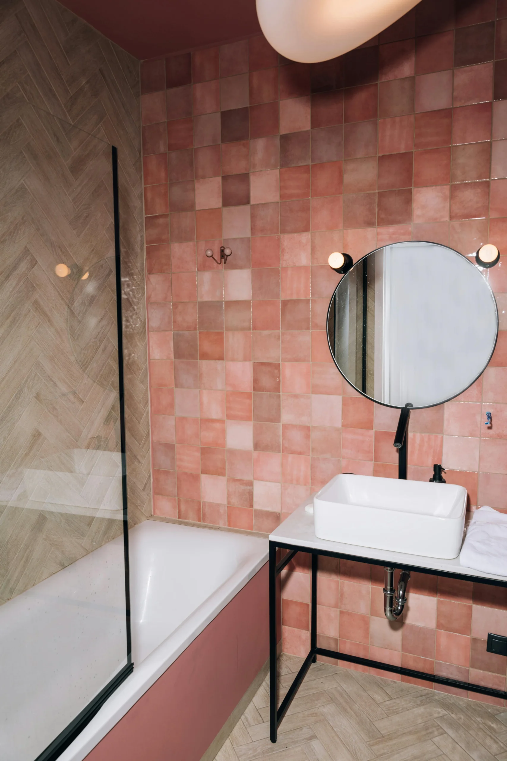 Baño Contemporáneo con Azulejos Rosados, Grifería Negra y Suelo de Espiga