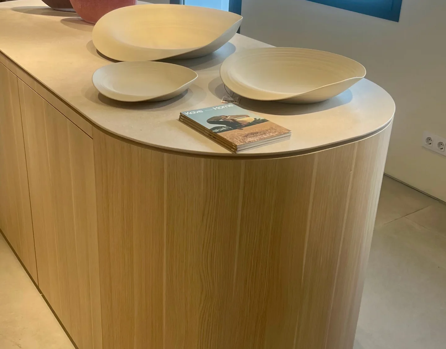 Isla de Cocina Curva en Madera Clara con Decoración Orgánica