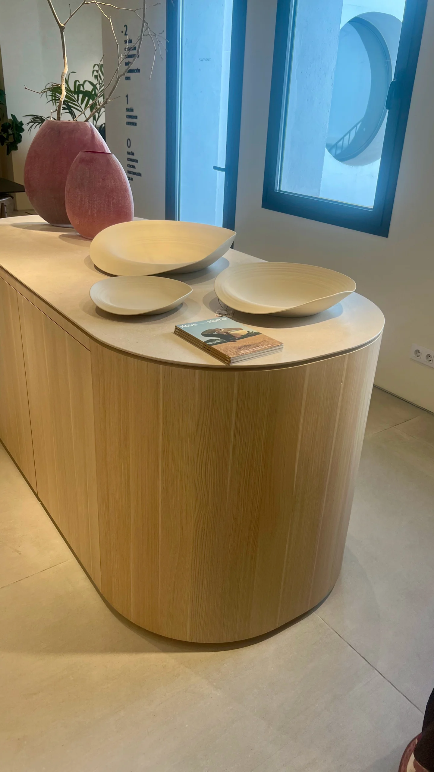 Isla de Cocina Curva en Madera Clara con Decoración Orgánica